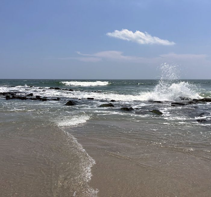 the Atlantic Ocean crashing upon rocks in Ocean City, NJ. The sandy beach is in the foreground