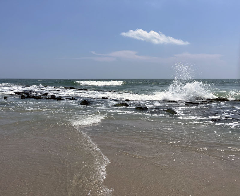 the Atlantic Ocean crashing upon rocks in Ocean City, NJ. The sandy beach is in the foreground