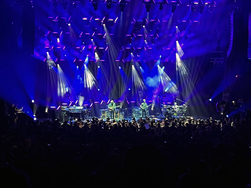 the band phish performing onstage. There are many lights and a haze of smoke