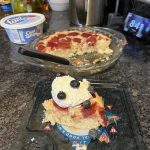 an unaesthetic photo of Smitten Kitchen's Strawberry cake with a dollop of Cool Whip and some blueberries on top. In the background is the entire cake and the tub of cool whip.