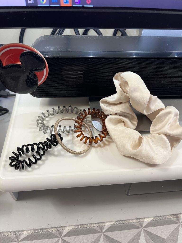 Five ponytail holders on my desk: three coiled ones, one traditional elastic and one satin scrunchie.