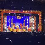 a lit up stage at HersheyPark: on the stage are costumed candy characters and dancers in sparkly costumes