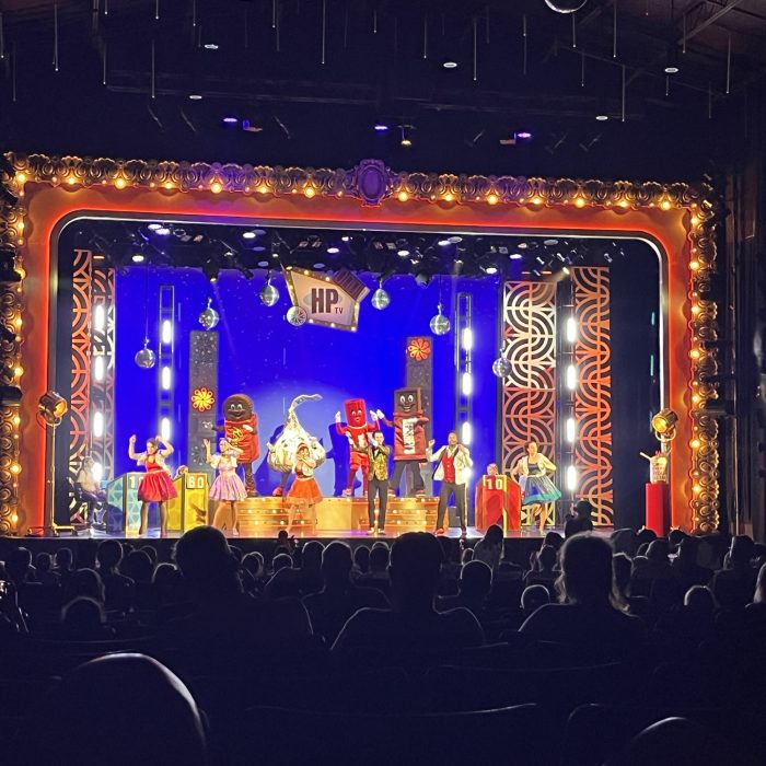 a lit up stage at HersheyPark: on the stage are costumed candy characters and dancers in sparkly costumes
