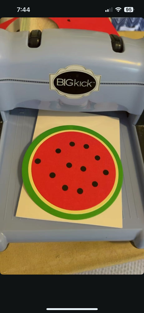 three colored paper circles nexted together to make a watermelon shape. it's sitting on the tray of a diecut machine.