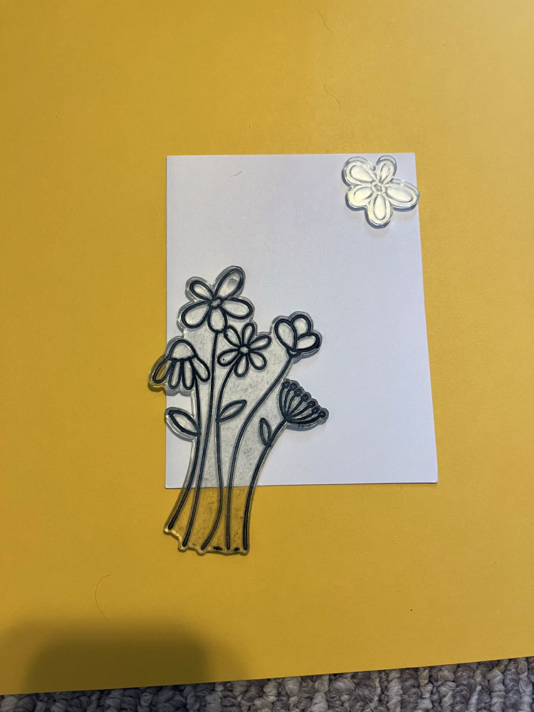a yellow background. on it is a card front with clear stamps positioned diagonally. 