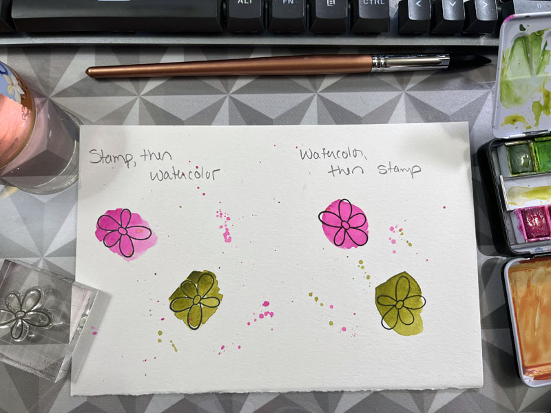 a test paper: on one side I have written "stamp, then watercolor" with two flowers stamped below it with watercolor on top of them. on the other side it says 'watercolor, then stamp' and the watercolor is behind the black ink of the pattern. There is scant difference.