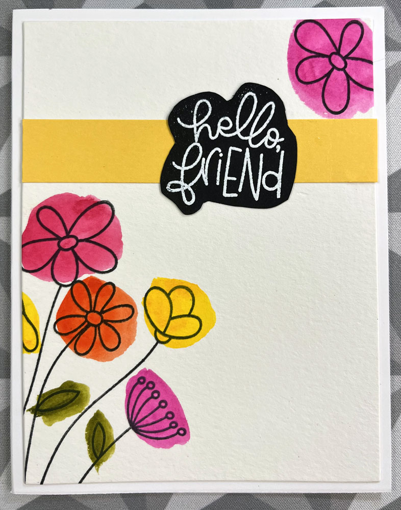 the completed card: stamped flowers with colorful spots of pink, yellow, and orange behind them, a yellow strip of paper about 1/4 down from the top and a 'hello friend' embossed in white on black paper, cut into a blob shape and adhered on top of the yellow strip