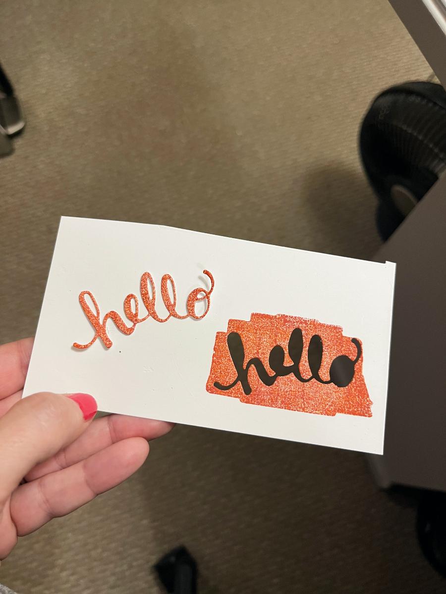 a cut out 'hello' greeting next to the inky mass that I cut it from