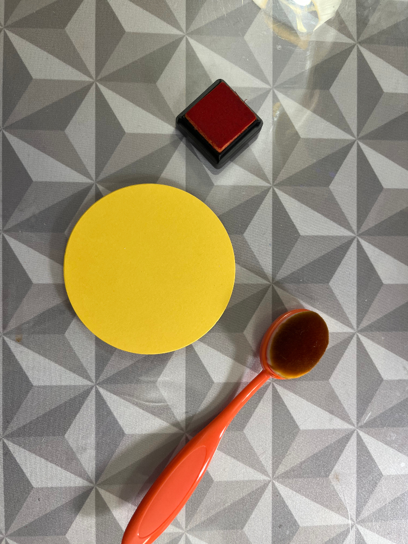 a yellow circle, orange ink, and a brush