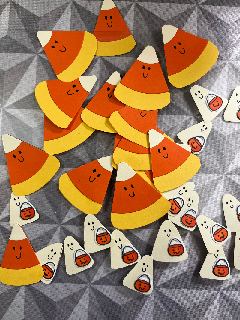 a pile of cut out ghost and candy corn pieces. They are all smilling