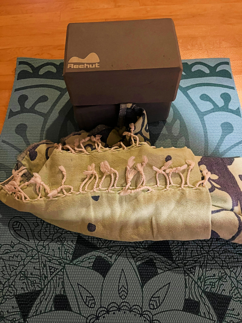 a blanket and two gray foam blocks on a blue yoga mat