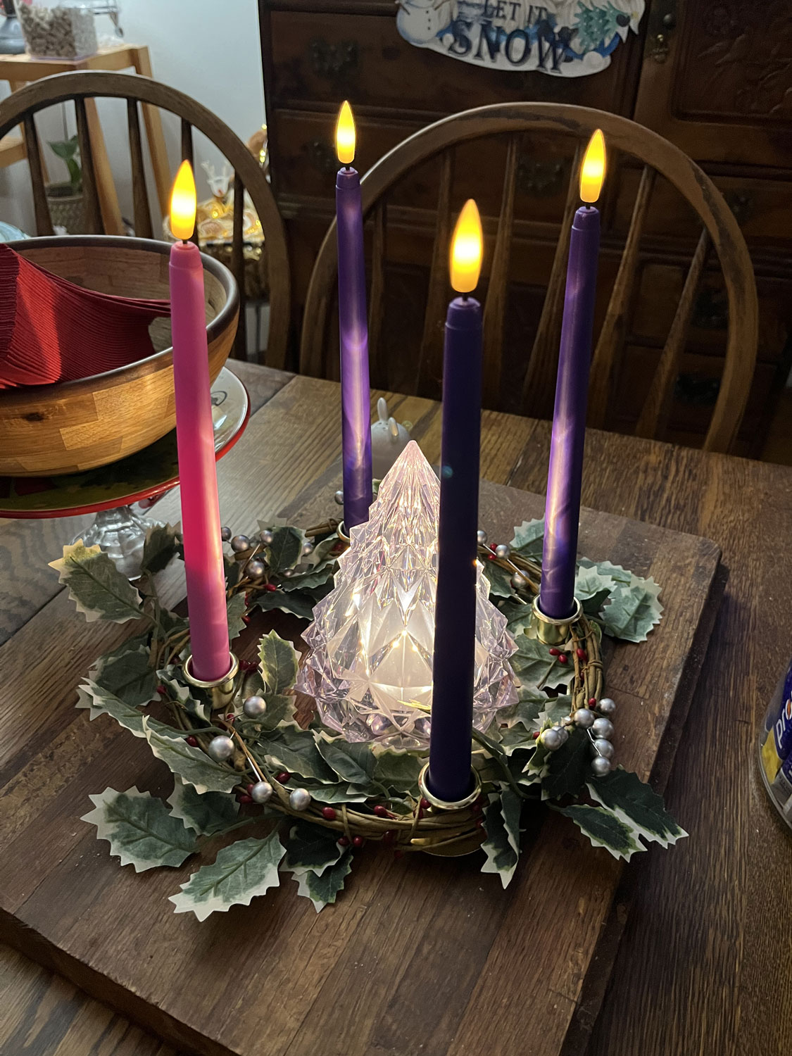 an advent wreath with 4 candles lit and an illuminated glass-ish tree in the middle.