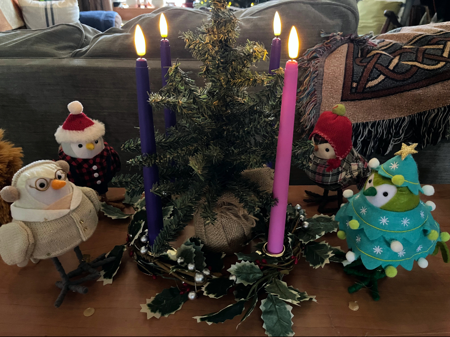 an advent wreath with four candles lit and four little bird decorations