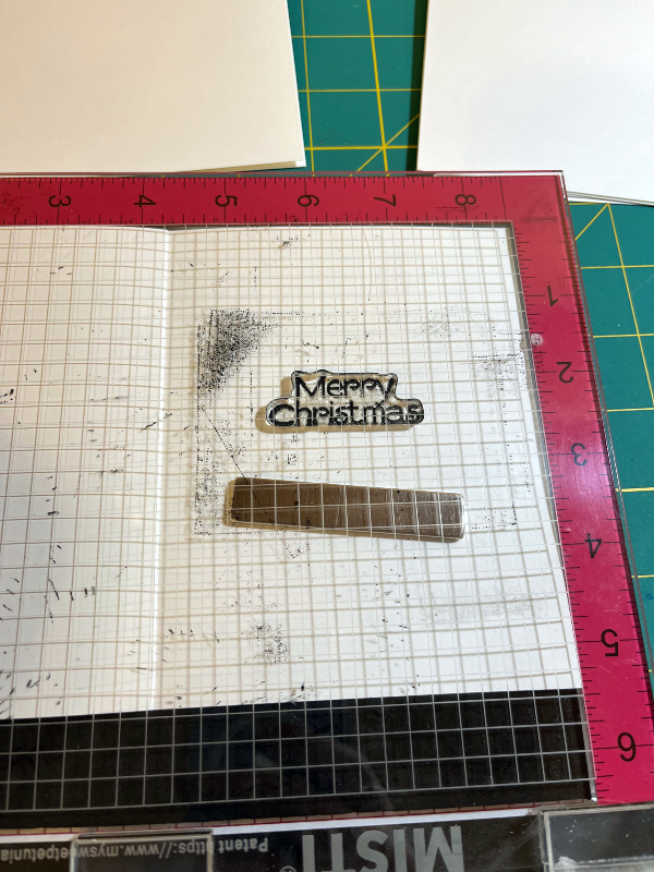 a card in a stamping tool with a Merry Christmas stamp