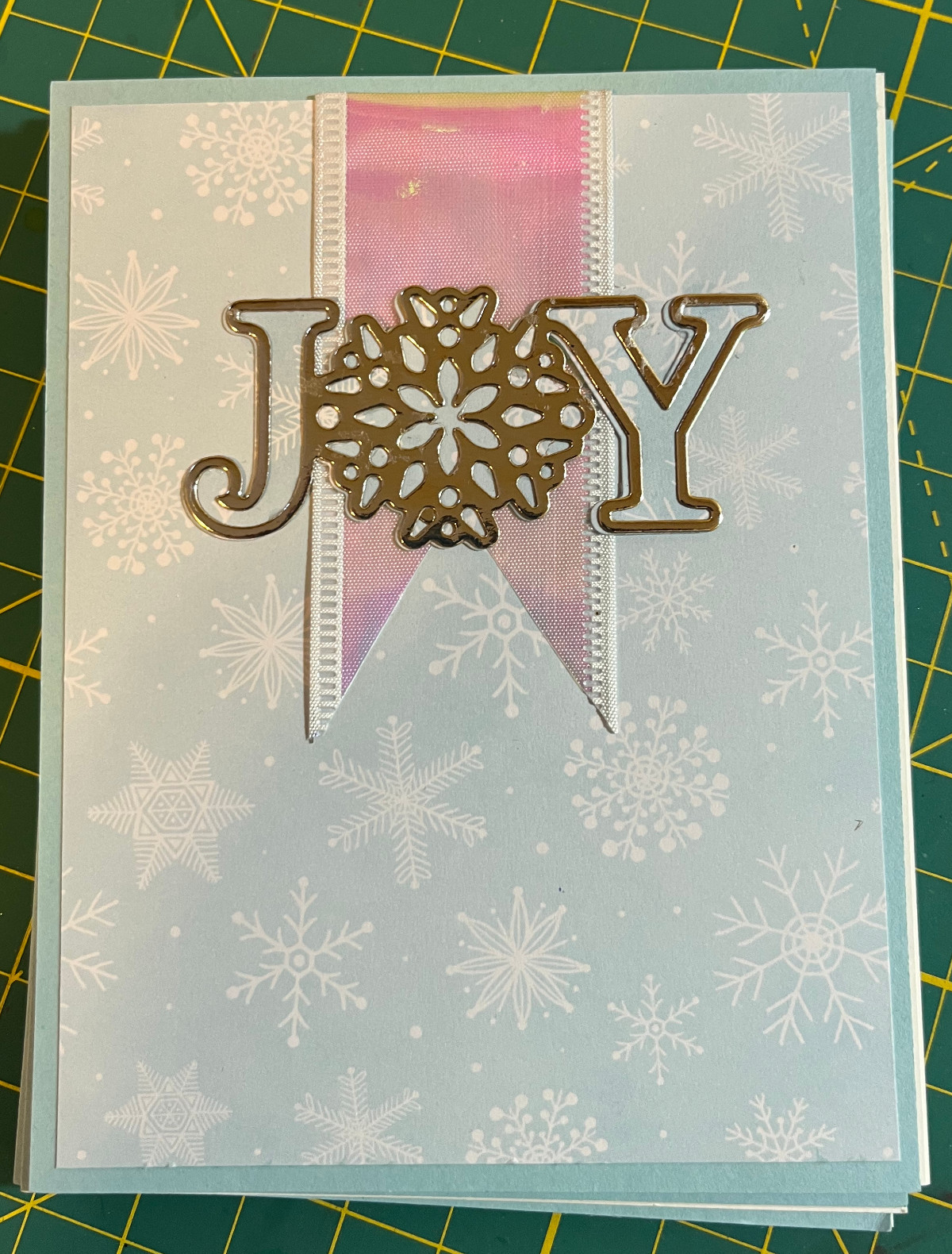 portrait card, blue paper with with snowflakes, white holographic ribbon, JOY in silver