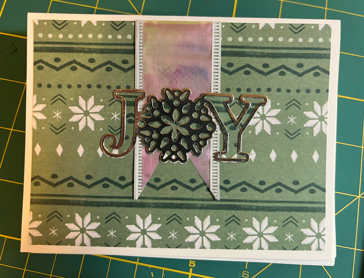 landscape orientation card with green patterned paper, a white holographic ribbon and silver JOY