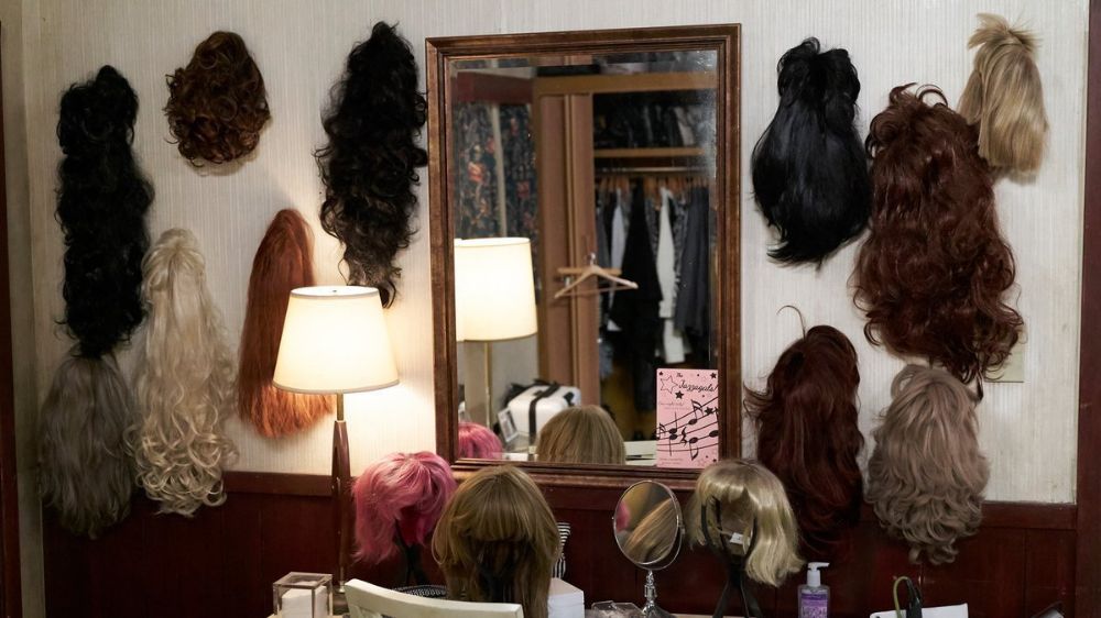 a scene from schitt's creek showing Moira's wig wall.