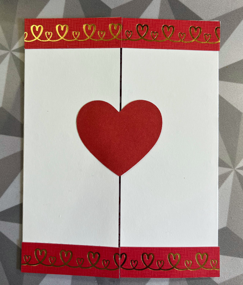 a valentine's card, with the opening in the middle instead of the edge. There is a red heart in the middle and printed paper lining the top and ottom