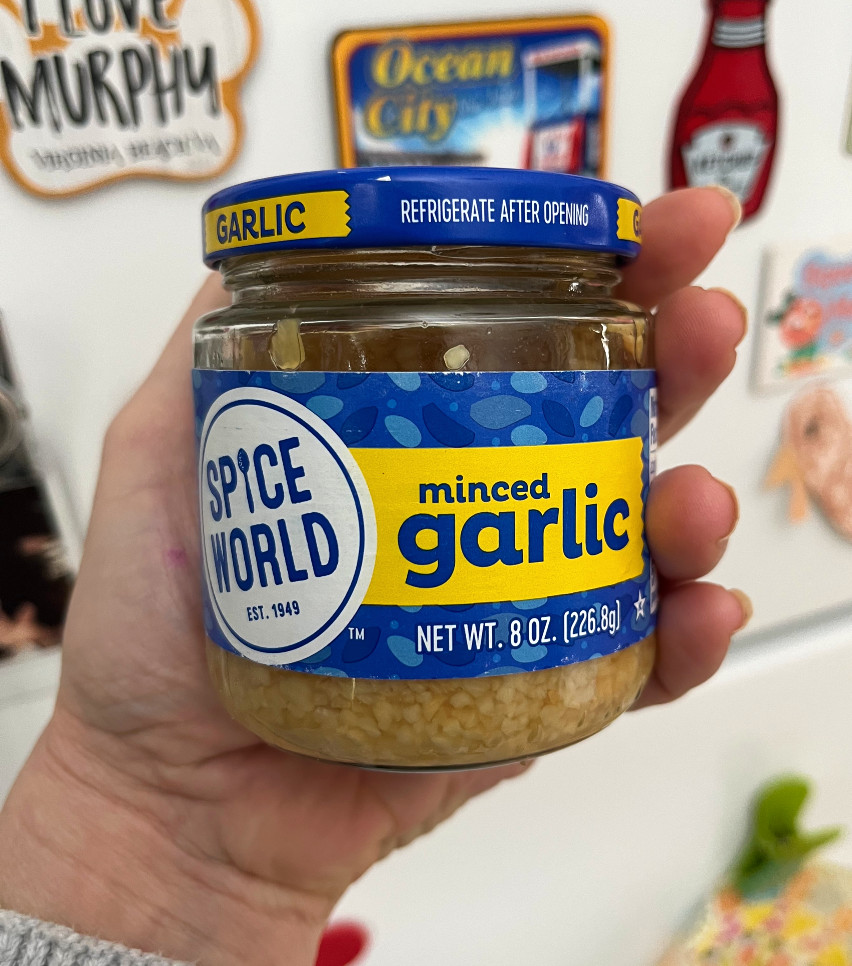 kim holding a jar of minced garlic, with her refrigerator door in the background