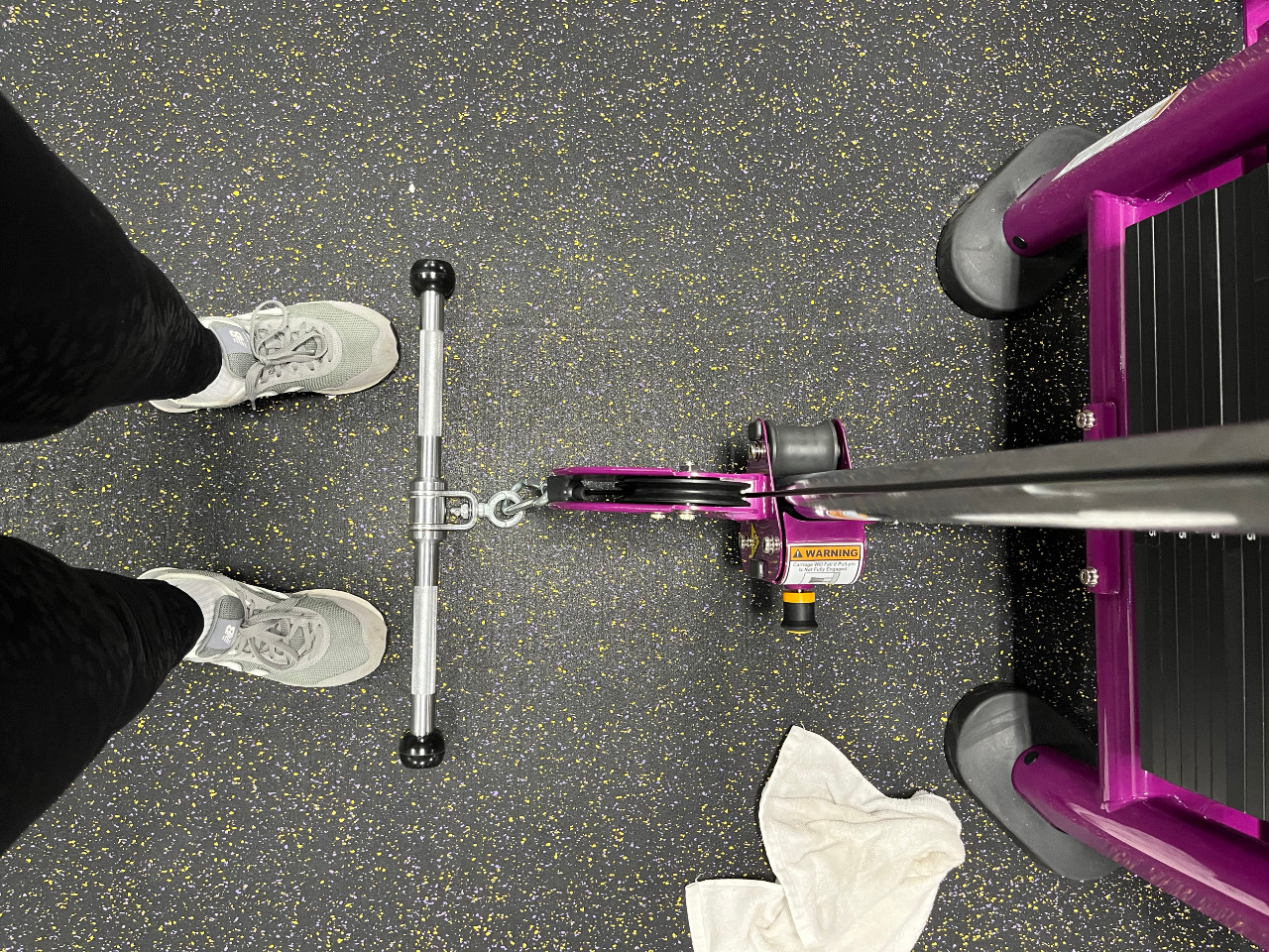 at left, kim's sneakers on the ground. center and right, a pullup bar attached to a fitness machine. Kim's white emotional support towel is on the ground as well.