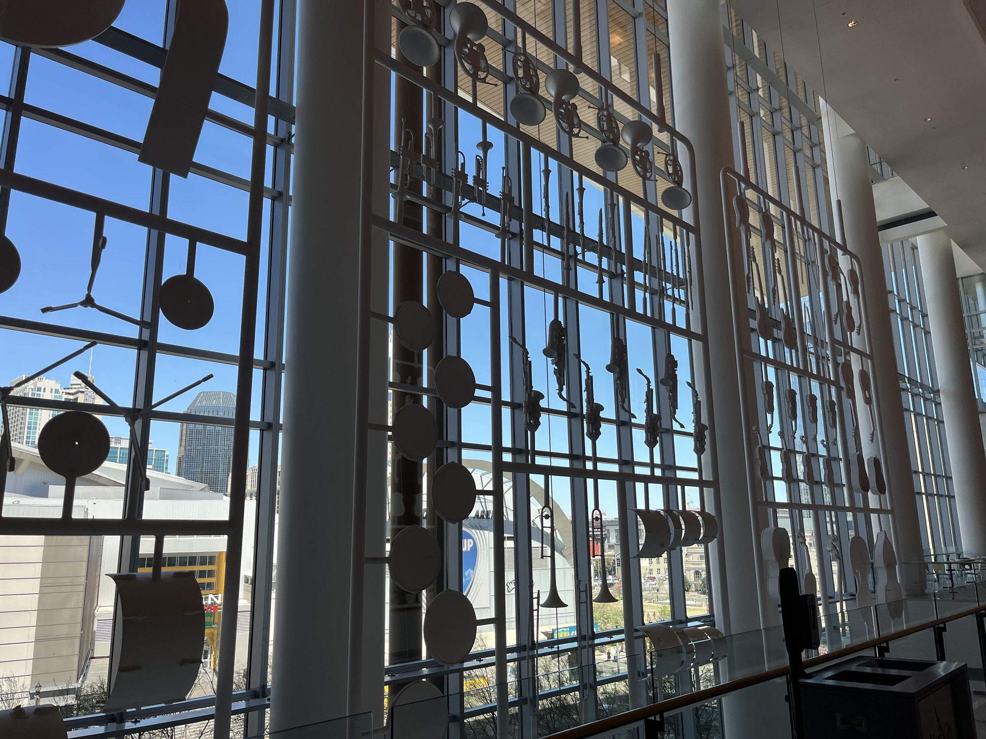 Inside the music city convention center in Nashville, looking at an art installation of music notes and instruments. The sky outside is blue. 
