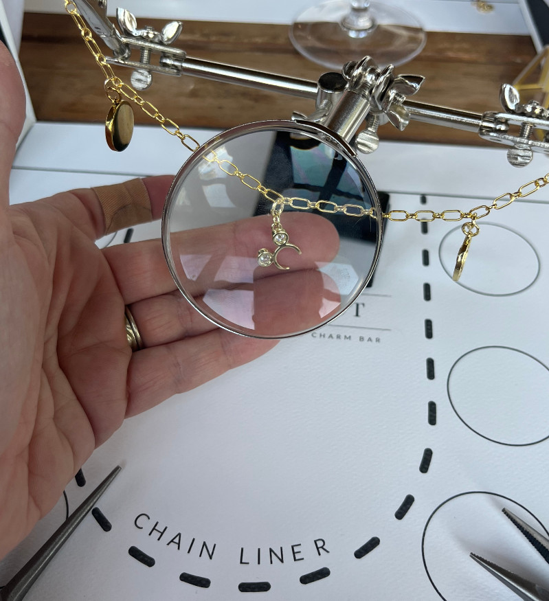 a mickey mouse charm being held beneath a magnifying glass at a bracelet making class