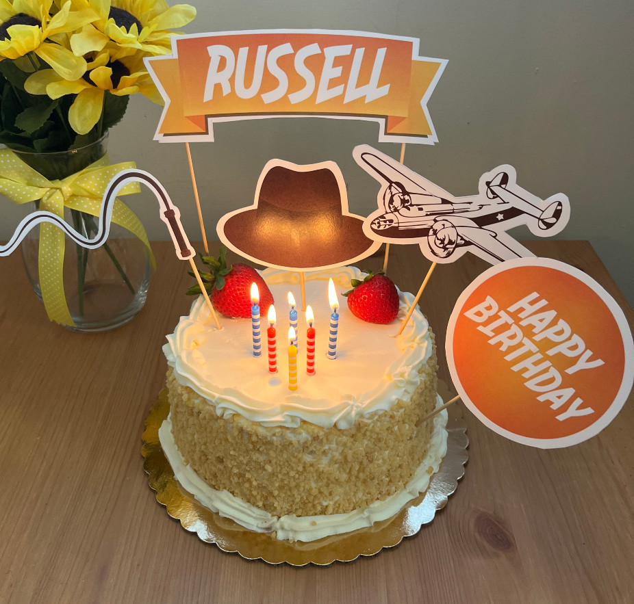 WM's birthday cake with Indiana Jones themed decor on it, the banner says RUSSELL