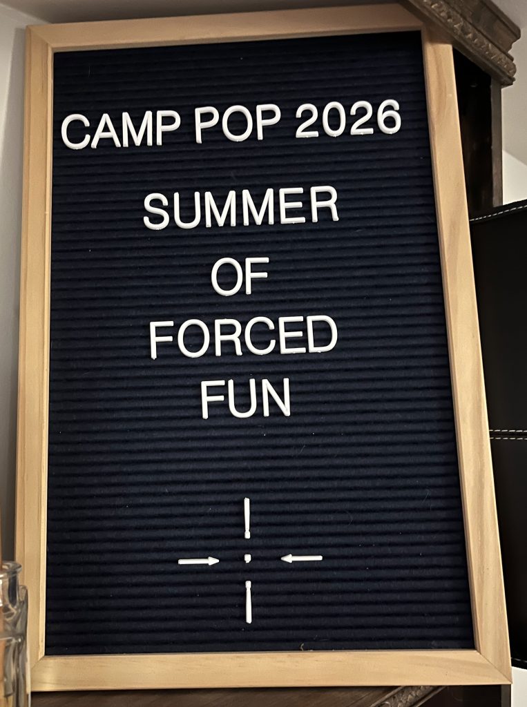 a very 2010s letterboard with "Camp Pop 2026 Summer of Forced Fun" on it.
